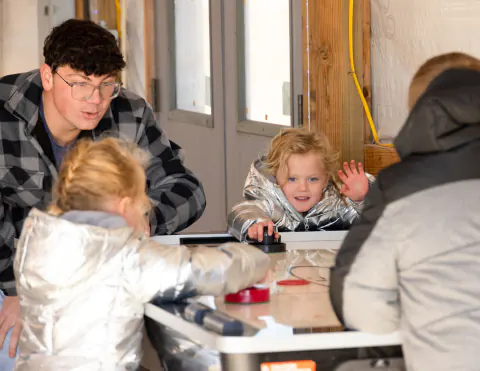 Children and a young man playing air hockey