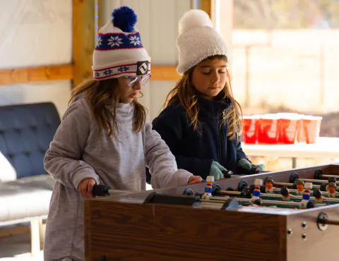 Two girls playing foosball in the game room