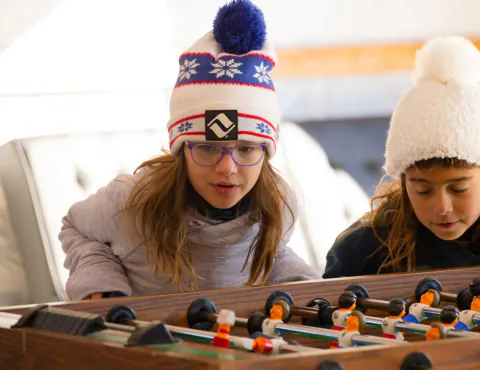 Two girls in knit hats playing foosball