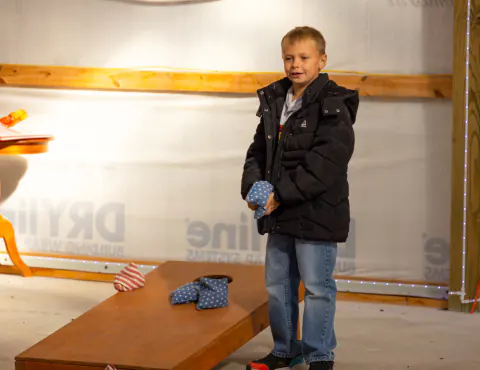 Boy playing cornhole in the game room