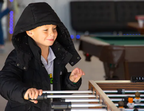 Boy in a hooded coat playing foosball