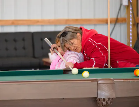 Grandmother helping a child with a billiards shot