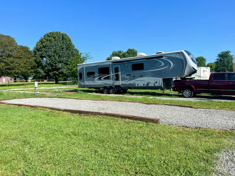 Fifth-wheel trailer beside an empty gravel RV site